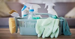 Household cleaning supplies in a basket with gloves and brushes.