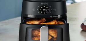 Philips air fryer with fried chicken inside, placed on a kitchen counter.