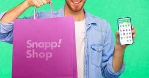 Smiling man holding Snapp Shop bag and phone with Snapp app open.