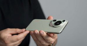 Close-up of a person holding a light green smartphone with a unique rear camera module.