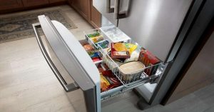 A bottom freezer filled with frozen foods and ice, integrated in a modern kitchen. 