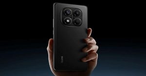 Hand holding a sleek black Redmi smartphone with a large quad-camera module, showcased against a dark background.
