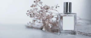 Minimalist perfume bottle with silver cap and delicate dried flowers on white background