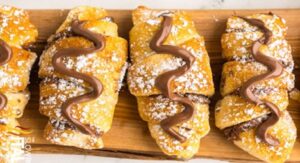  Chocolate-filled croissants topped with powdered sugar and chocolate drizzle.