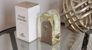 Voyage d'Hermès Eau de Toilette bottle and packaging on a reflective surface with decorative sphere