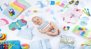 Smiling baby surrounded by colorful newborn essentials like clothes, toys, towels, and bottles. 