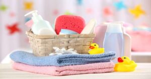 Baby bath essentials with towels, rubber ducks, sponge, and toiletries in a wicker basket. 