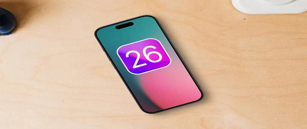 iPhone on table displaying iOS 26 logo on screen