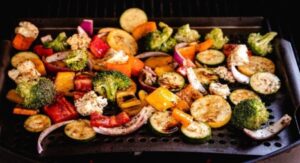Colorful seasoned vegetables grilling in an air fryer basket.