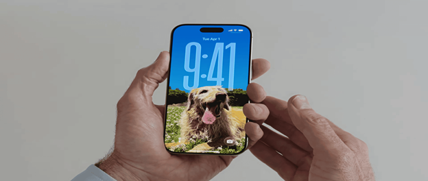 Person holding iPhone showing iOS 26 lock screen with dog wallpape