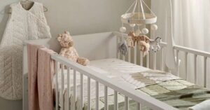 White baby crib with plush toys and soft bedding in a cozy neutral-toned nursery. 