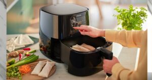 Woman using Philips air fryer to cook spring rolls on kitchen counter