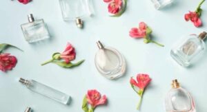 Assorted women's perfume bottles with pink flowers on a light blue background. 