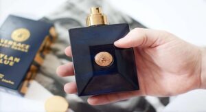 Hand holding Versace Dylan Blue perfume bottle with packaging in background