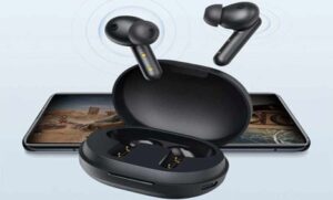 Black wireless earbuds with open case in front of smartphone on light background.