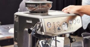 Hand operating Breville espresso machine with built-in coffee grinder.