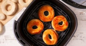 Golden brown donuts cooking in an air fryer basket.