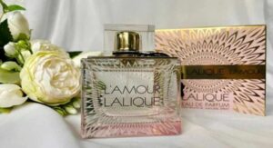 Lalique L'Amour perfume bottle with floral box and white roses in the background. 
