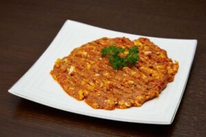 Persian Mirza Ghasemi eggplant dish served on a white plate.