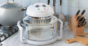 Glass convection oven on kitchen counter beside cookware and knife block.

