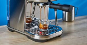 Dual espresso shots pouring into glass cups from a stainless steel espresso machine.

