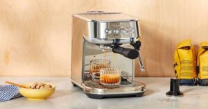 Breville espresso machine brewing two shots into glass mugs on a kitchen counter.