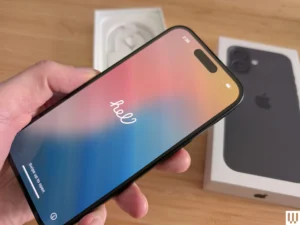 Hand holding new iPhone with “Hello” screen during initial setup.