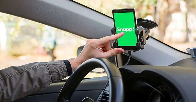 Driver using the Snapp app on a smartphone inside a car.