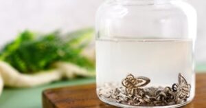 silver jewelry soaking in a glass jar with cleaning solution 