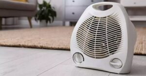 Portable electric fan heater placed on living room floor.