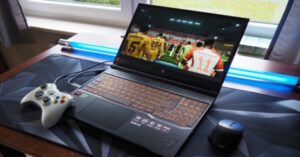 Gaming laptop displaying a soccer game with an Xbox controller and blue light.