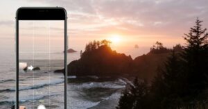 iPhone camera screen framing a sunset over the ocean and forested islands.