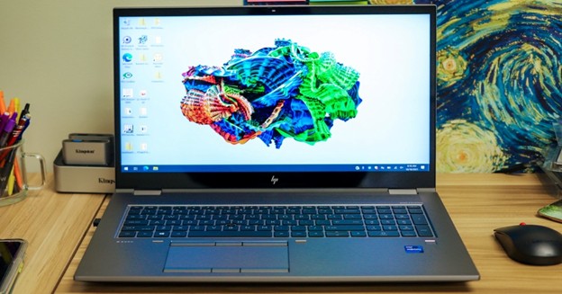 Large professional laptop displaying colorful abstract digital art wallpaper.