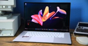 Silver laptop with white keyboard displaying colorful 3D abstract art.