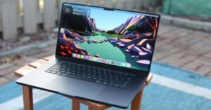 MacBook Pro displaying a colorful wallpaper on a wooden chair outdoors.