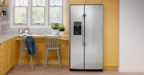 Stainless steel side-by-side refrigerator in a kitchen with yellow cabinets.
