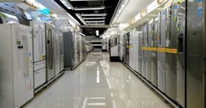 A brightly lit appliance store aisle lined with rows of refrigerators.