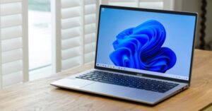 Silver laptop displaying the Windows 11 desktop on a wooden desk.