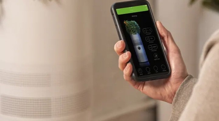 Hand using a smartphone app to control and monitor a smart air purifier.