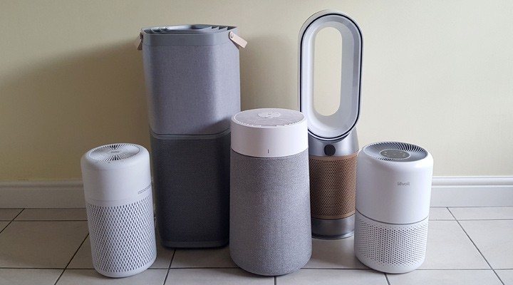 Group of five different modern home air purifier models lined up against a wall.