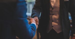 Two businessmen in suits shaking hands to seal a deal.