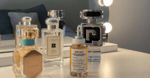 A collection of various perfume bottles on a brightly lit vanity table.