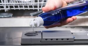 Pouring rinse aid into the dishwasher dispenser to prevent water spots