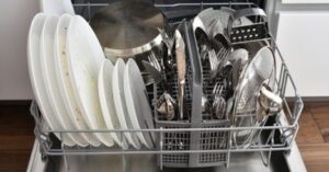 Overloaded dishwasher with dirty plates and utensils causing poor washing results