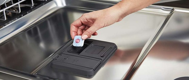 Placing a dishwasher detergent tablet into the detergent dispenser