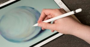 Hand holding Apple Pencil drawing a soft abstract circle on an iPad.