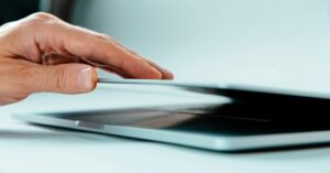 Hand closing laptop lid carefully on a desk 