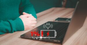 Laptop with 1% battery warning icon while plugged in on desk 