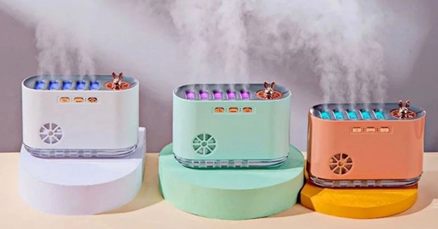 Three colorful humidifiers producing mist on display stands