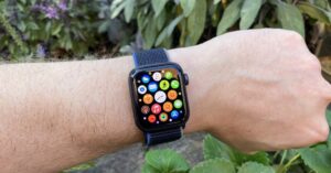 Apple Watch on wrist showing colorful app icons outdoors